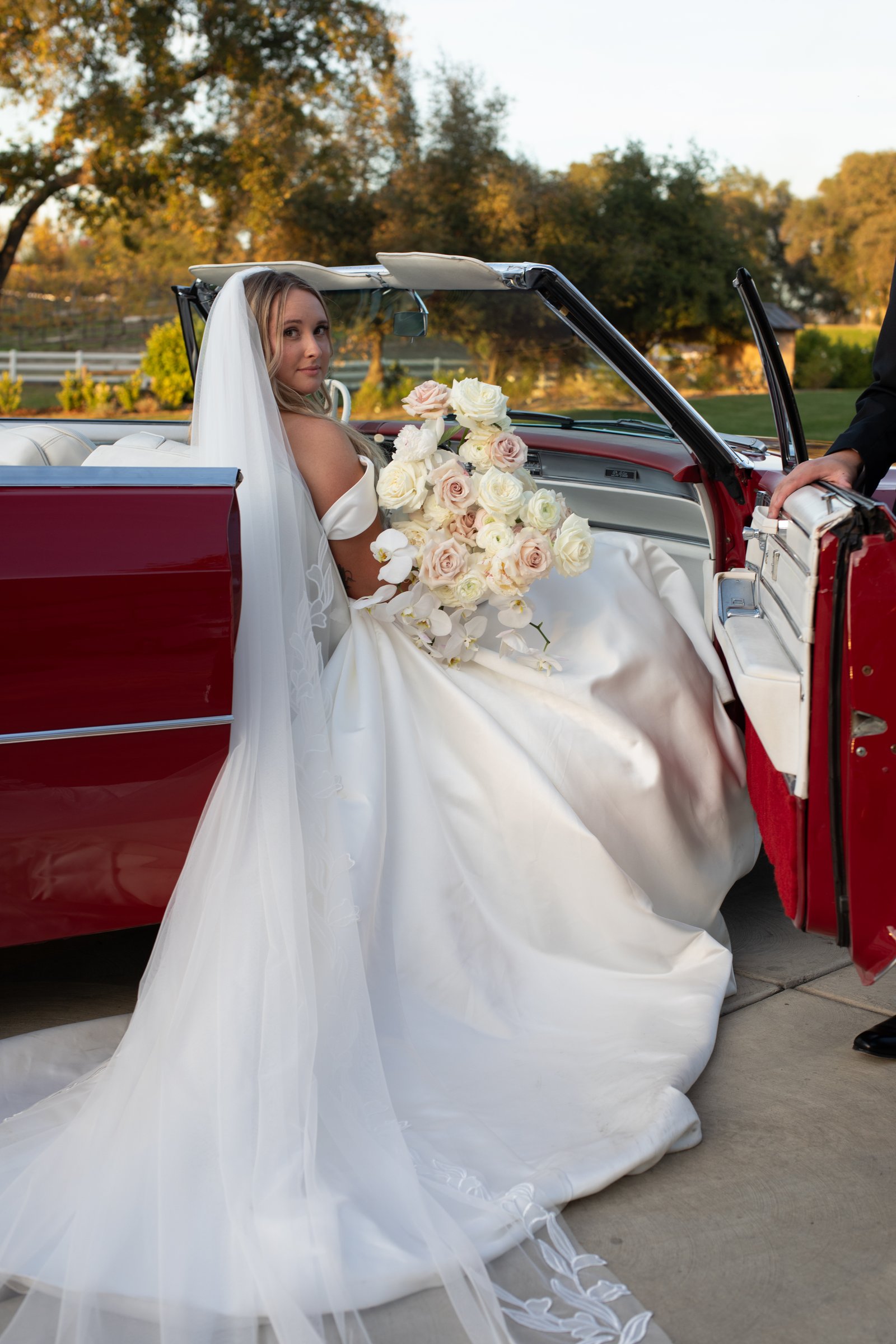 Bride in vintage car with bouquet